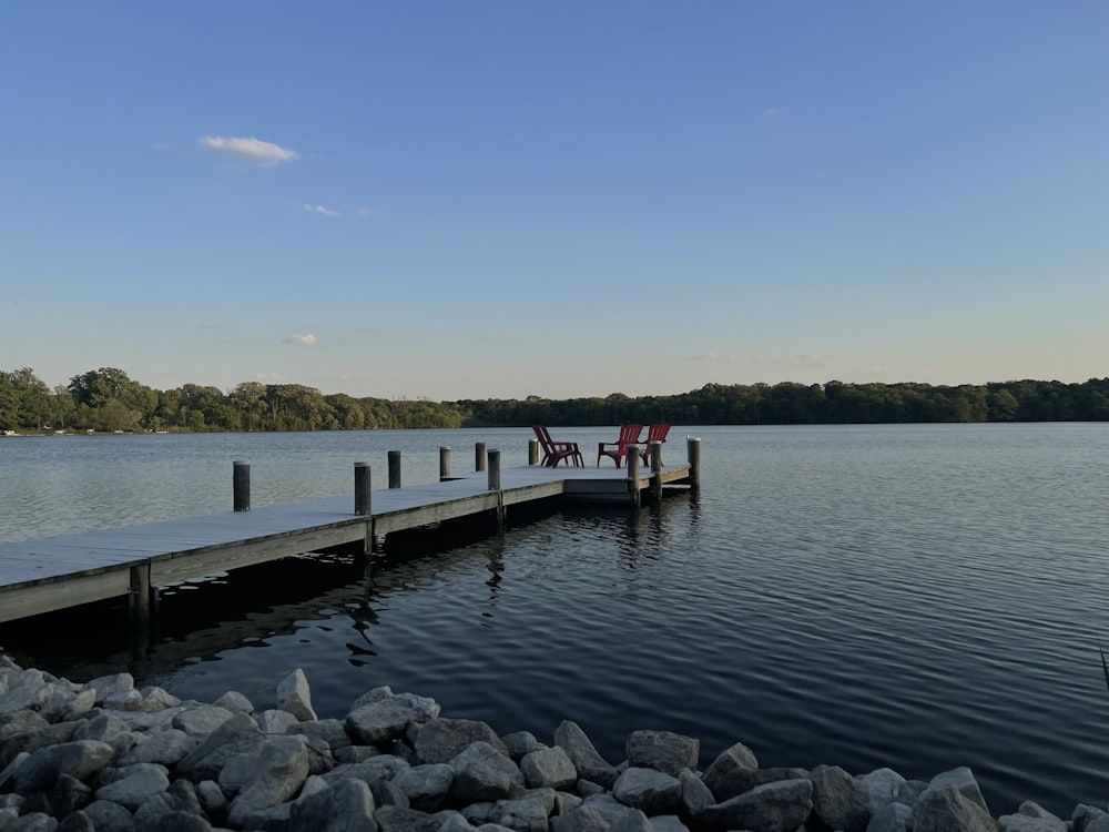 a dock on a lake with two chairs on it