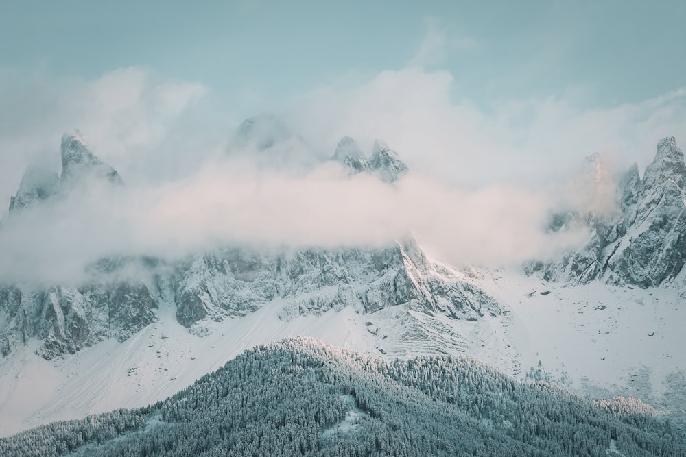 a mountain covered in snow and clouds under a cloudy sky