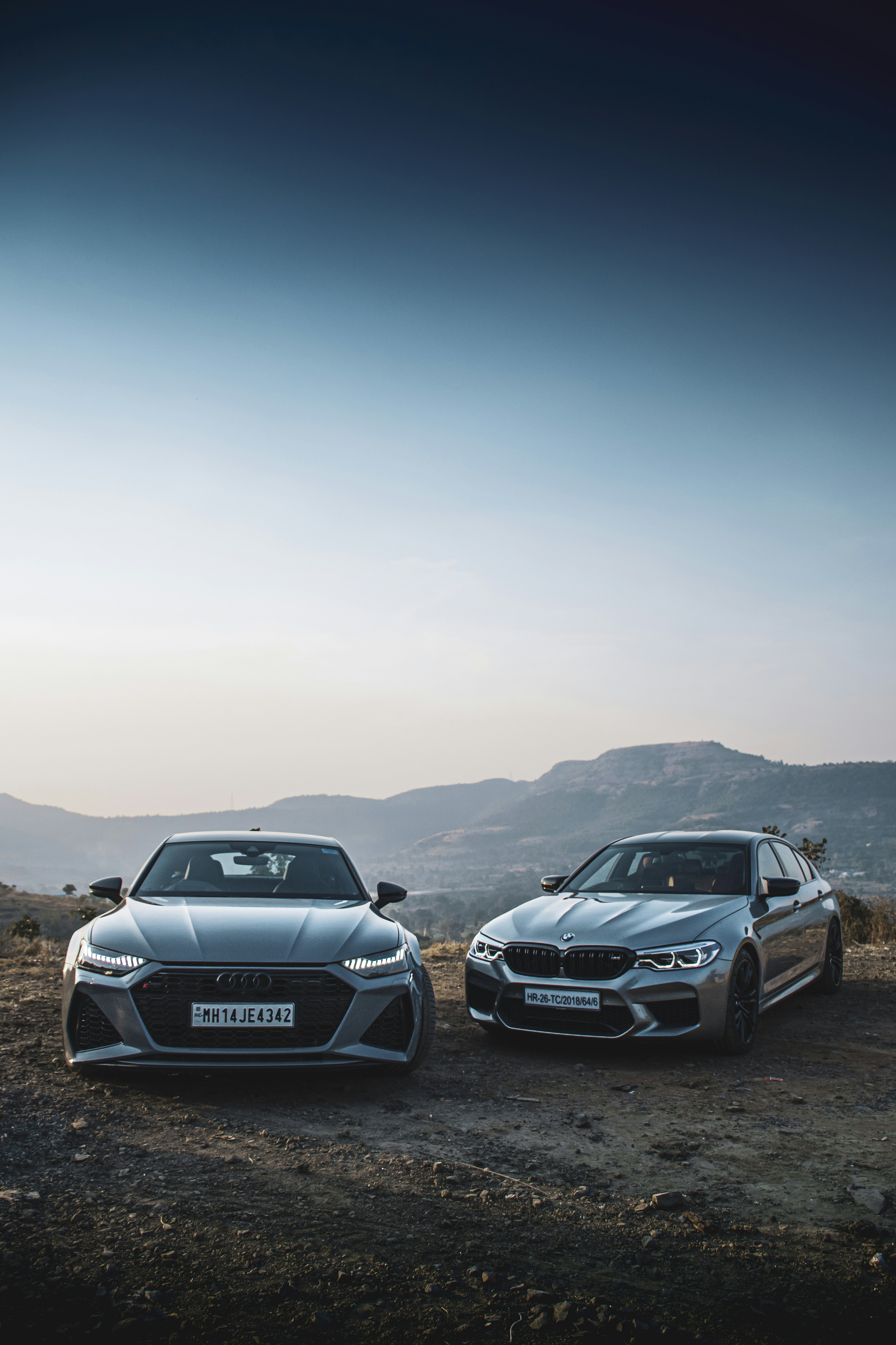 a couple of cars parked on top of a dirt field