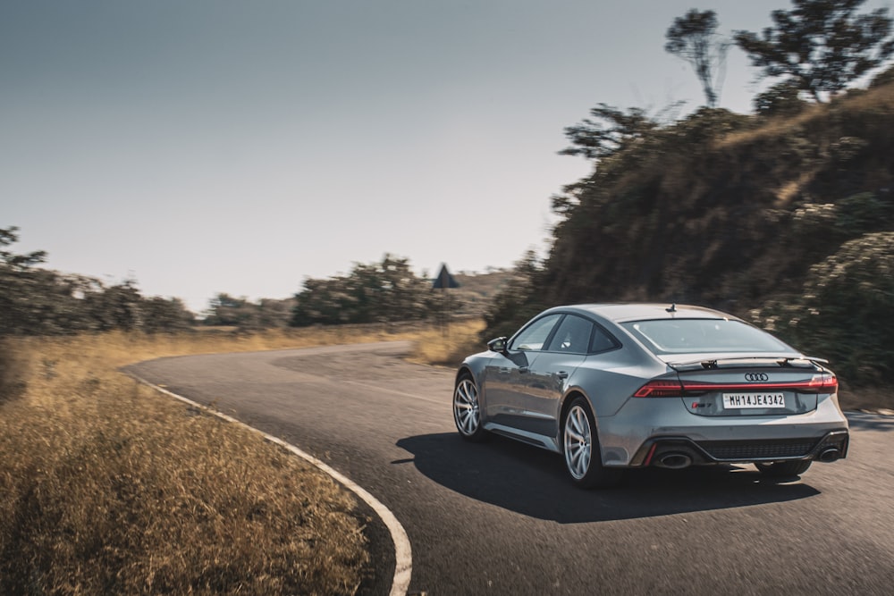 a silver car driving down a winding road