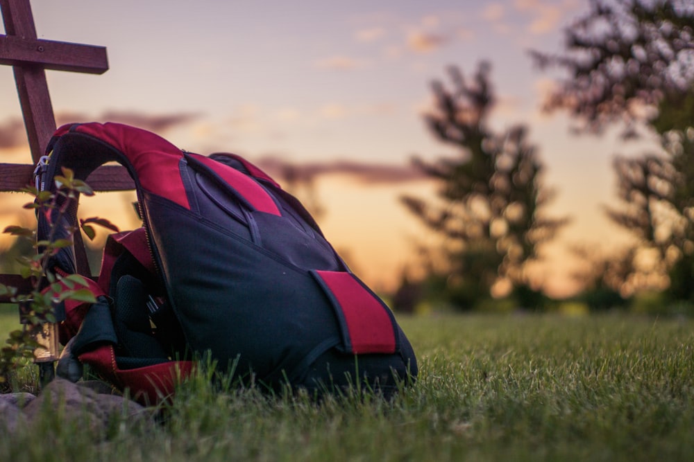 a backpack sitting in the grass next to a cross