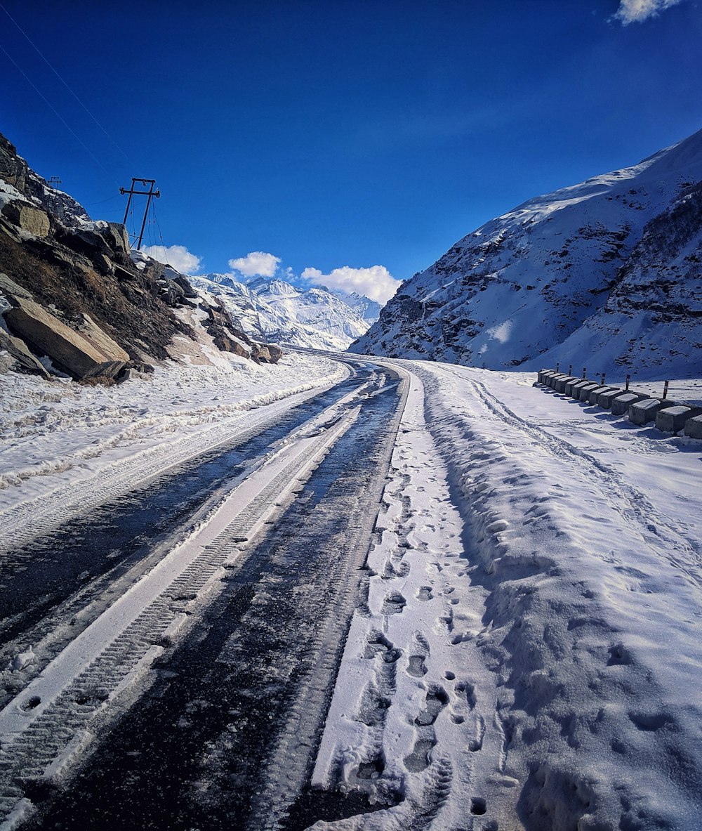 a snow covered road with mountains in the background