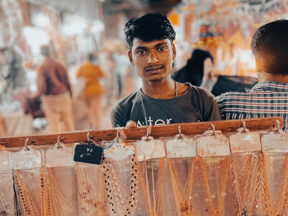 a man standing in front of a display of necklaces