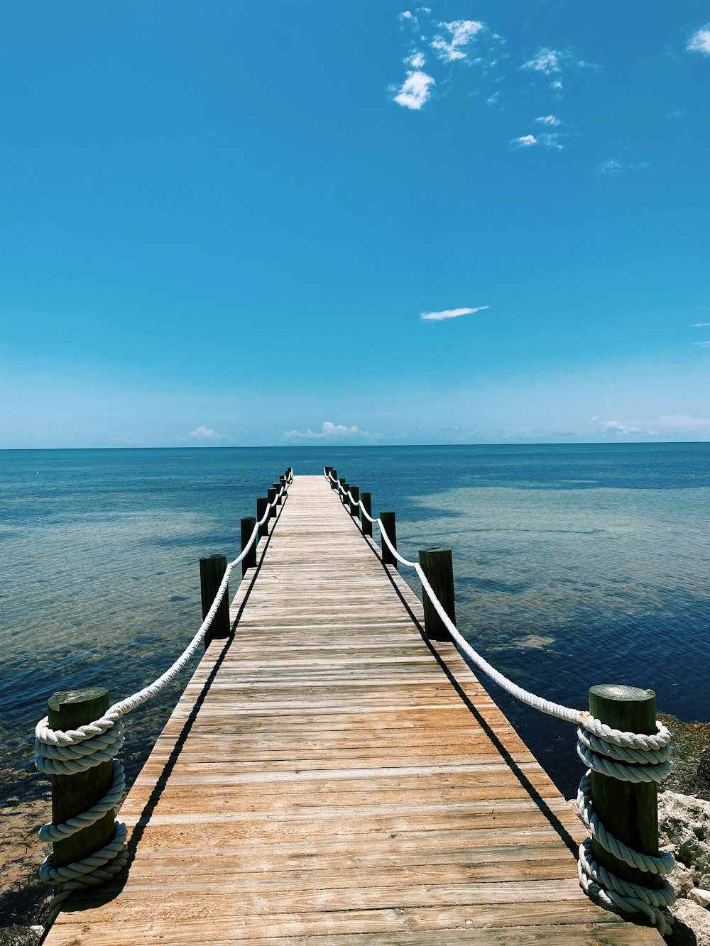 a wooden pier extending into the ocean on a sunny day