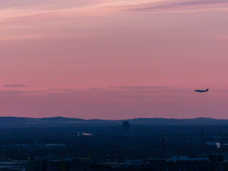 Sleek light jet soaring above a coastal European city at sunset.