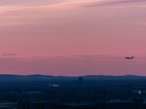 Sleek light jet soaring above a coastal European city at sunset.