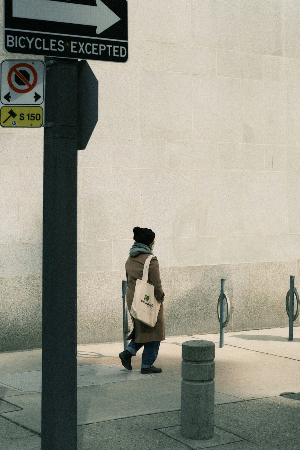 a person walking down a sidewalk next to a street sign