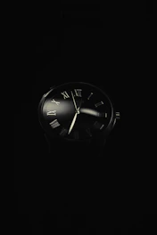 a black and white photo of a clock in the dark