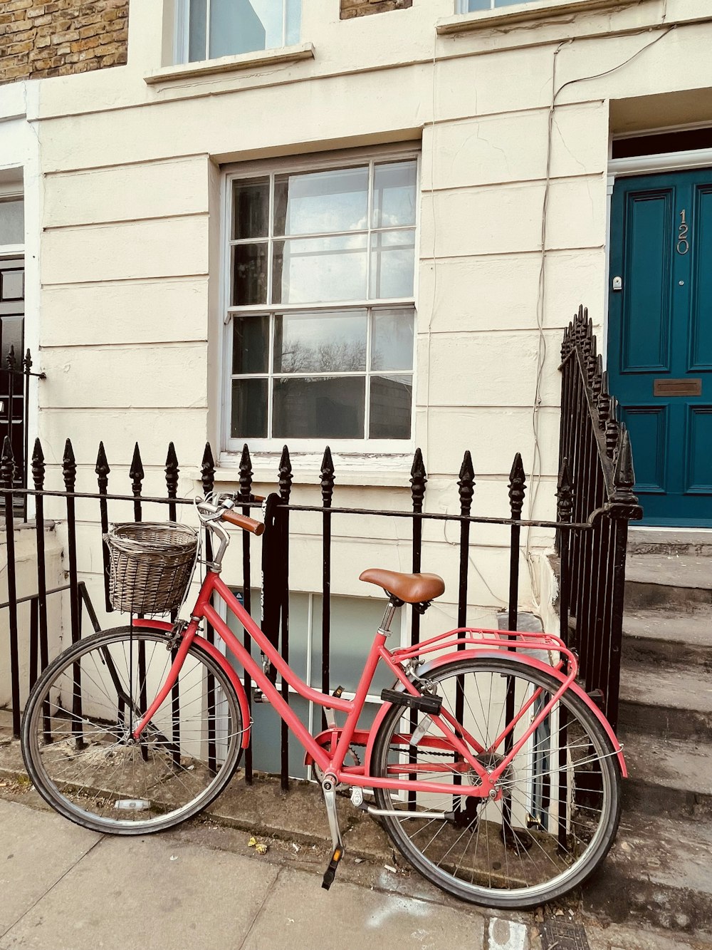 a red bicycle parked next to a black fence