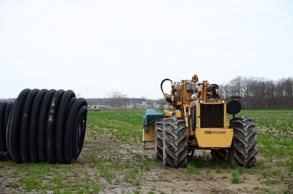 a tractor parked next to a large tire in a field