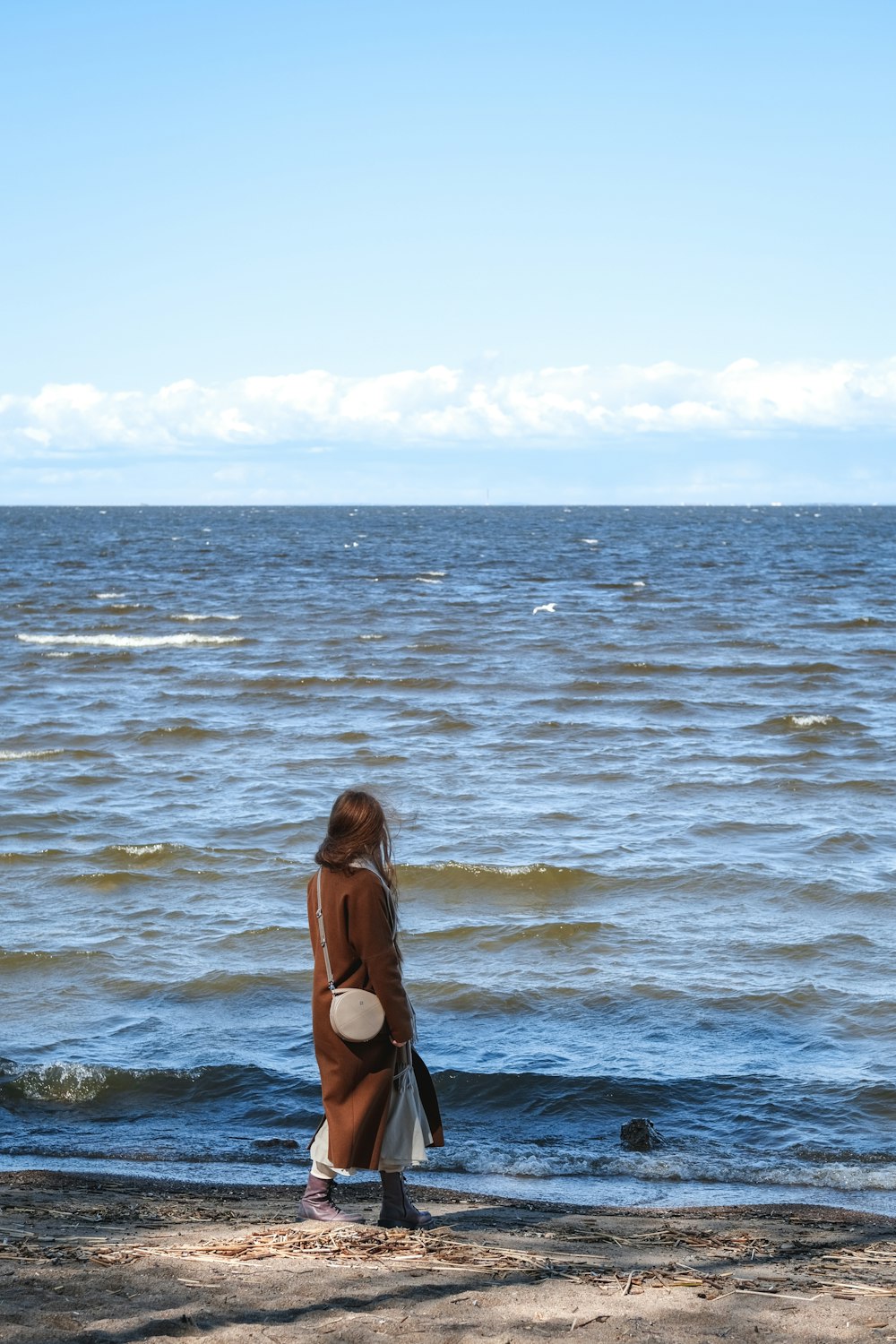 Eine Frau steht an einem Strand am Meer