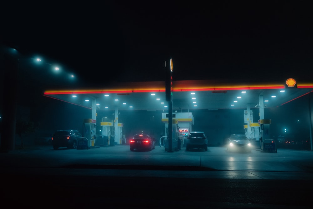 a gas station at night with cars parked at the gas pump