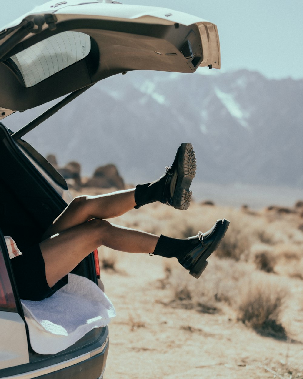 a woman sitting on the back of a car in the desert