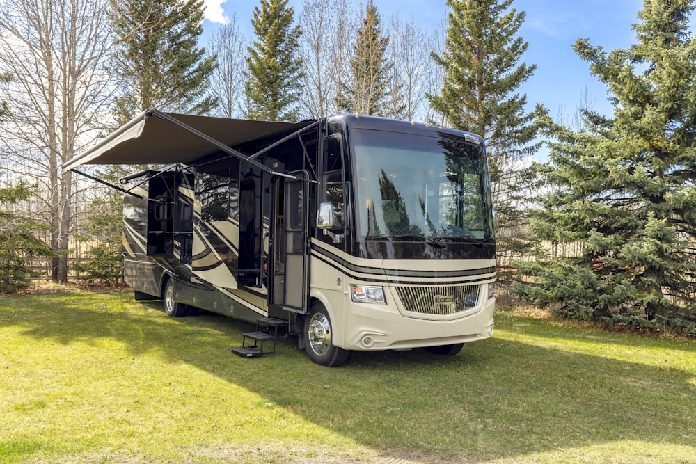 a motor home parked in the grass near some trees