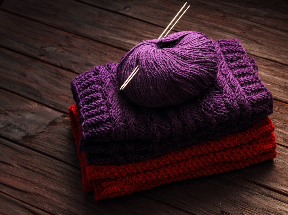 a pile of purple and red yarn sitting on top of a wooden table