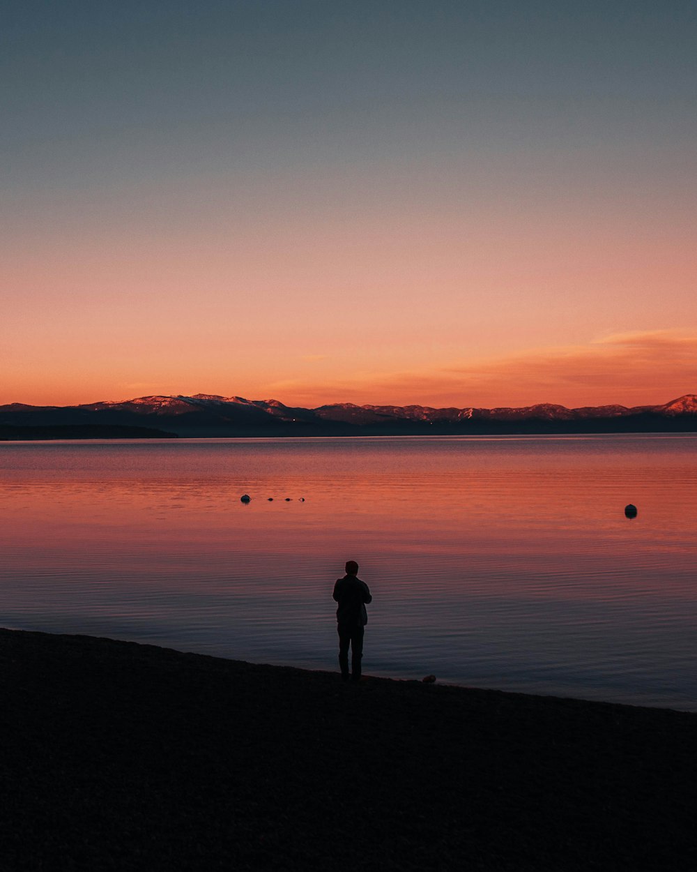 a person standing on a beach next to a body of water