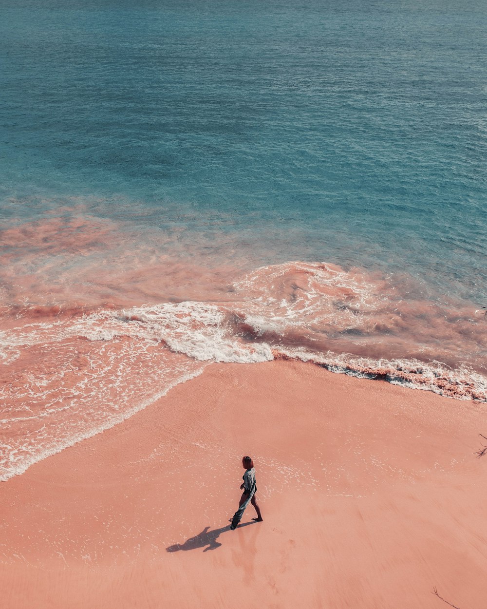 海の近くのビーチを歩いている人
