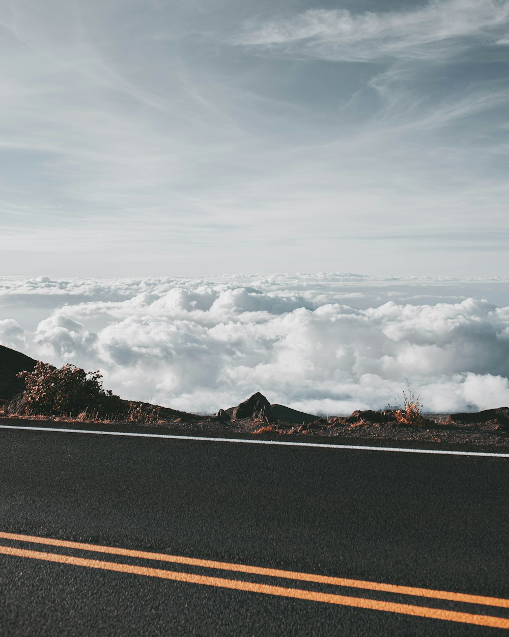 uma estrada com uma montanha ao fundo e nuvens no céu