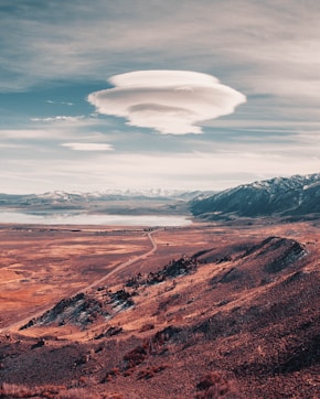 a long road going through a desert with mountains in the background