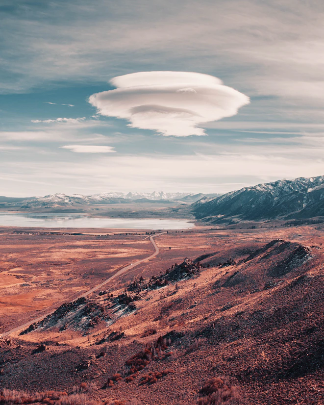 a long road going through a desert with mountains in the background