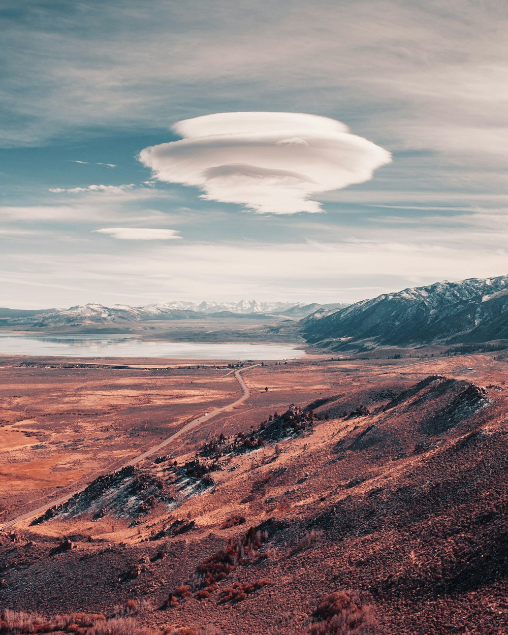 a long road going through a desert with mountains in the background