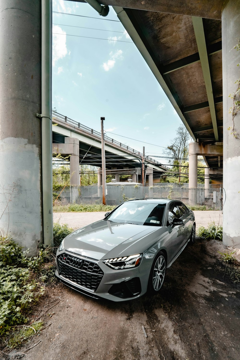 a silver car is parked under a bridge