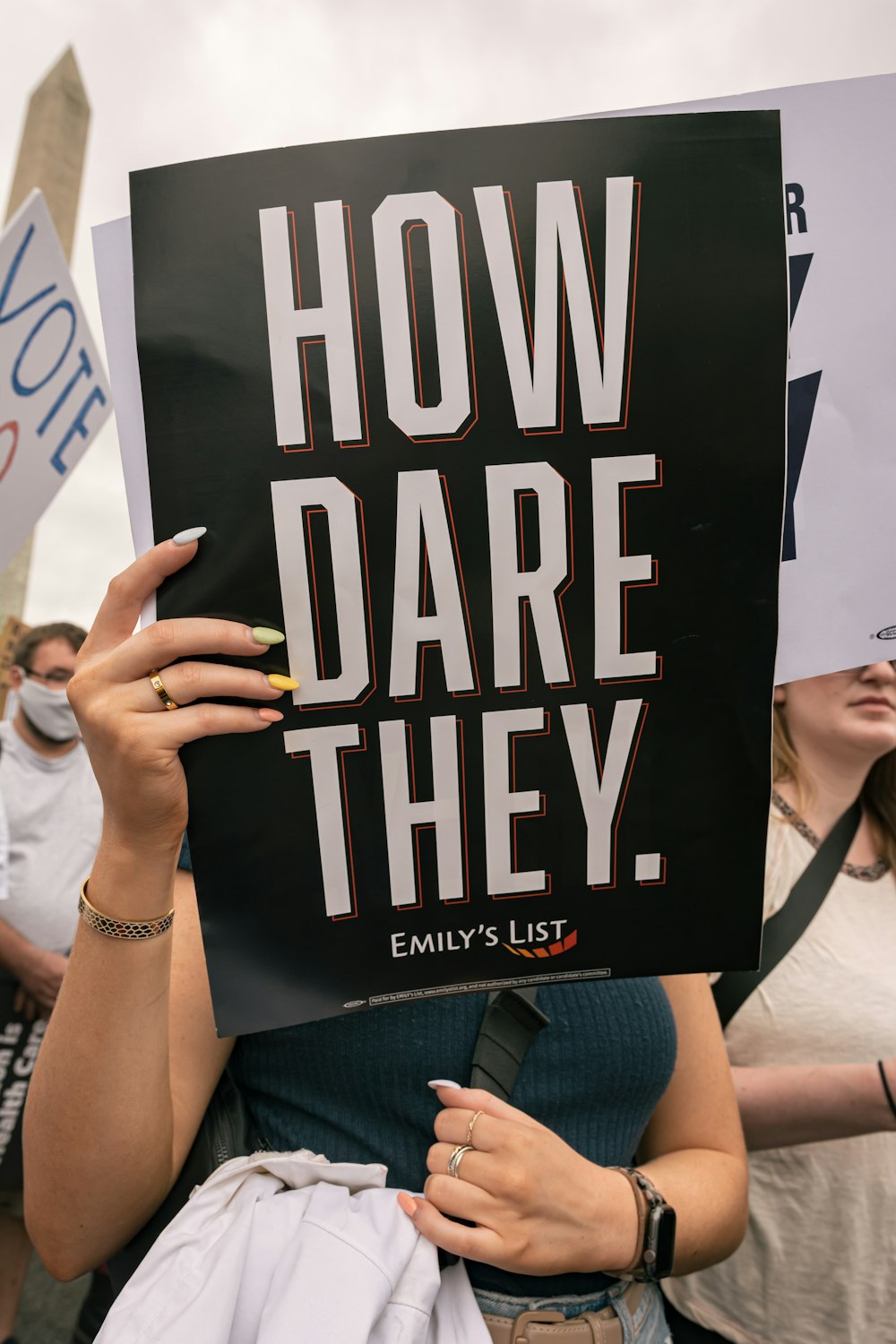 a woman holding a sign that says how dare they