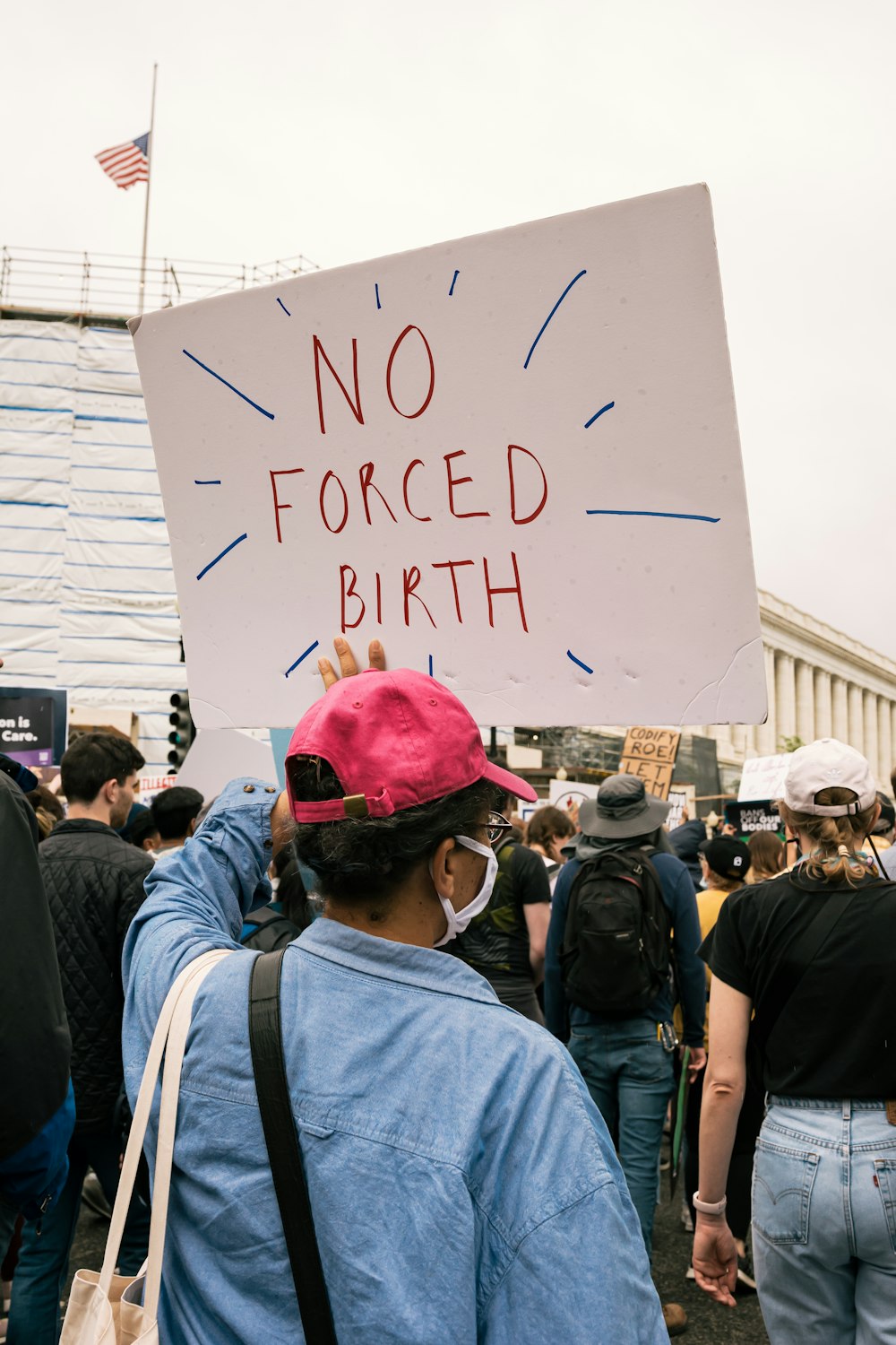 a person holding a sign that says no forced birth