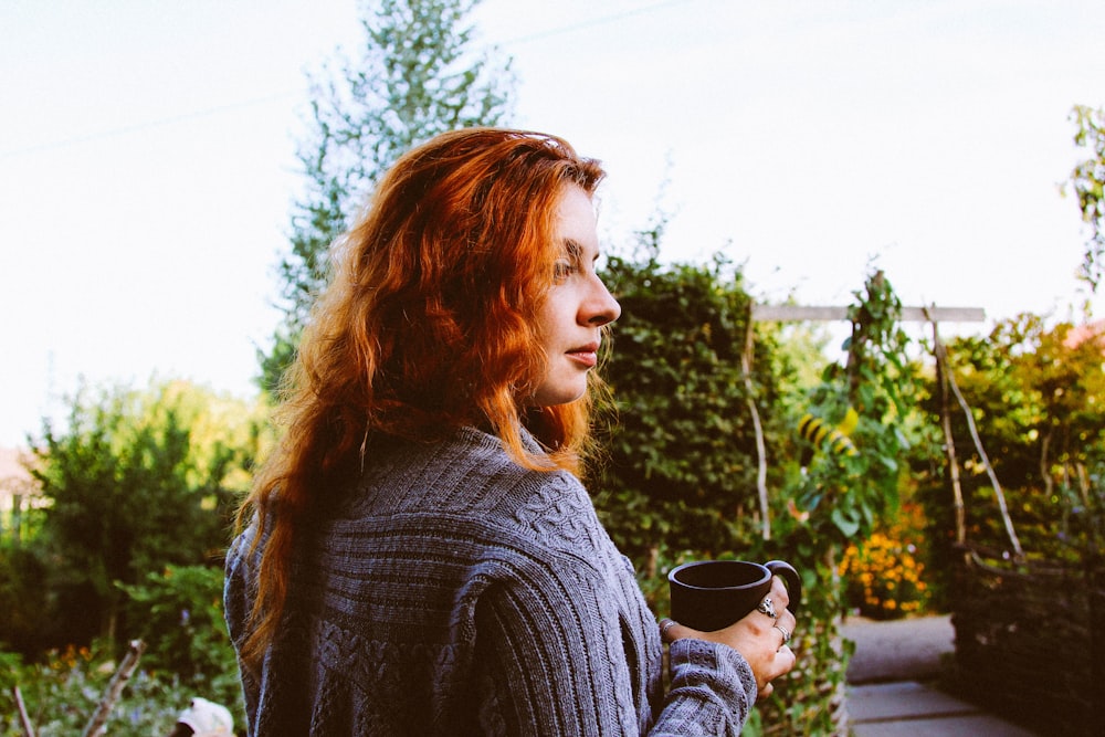 a woman with red hair is holding a coffee cup