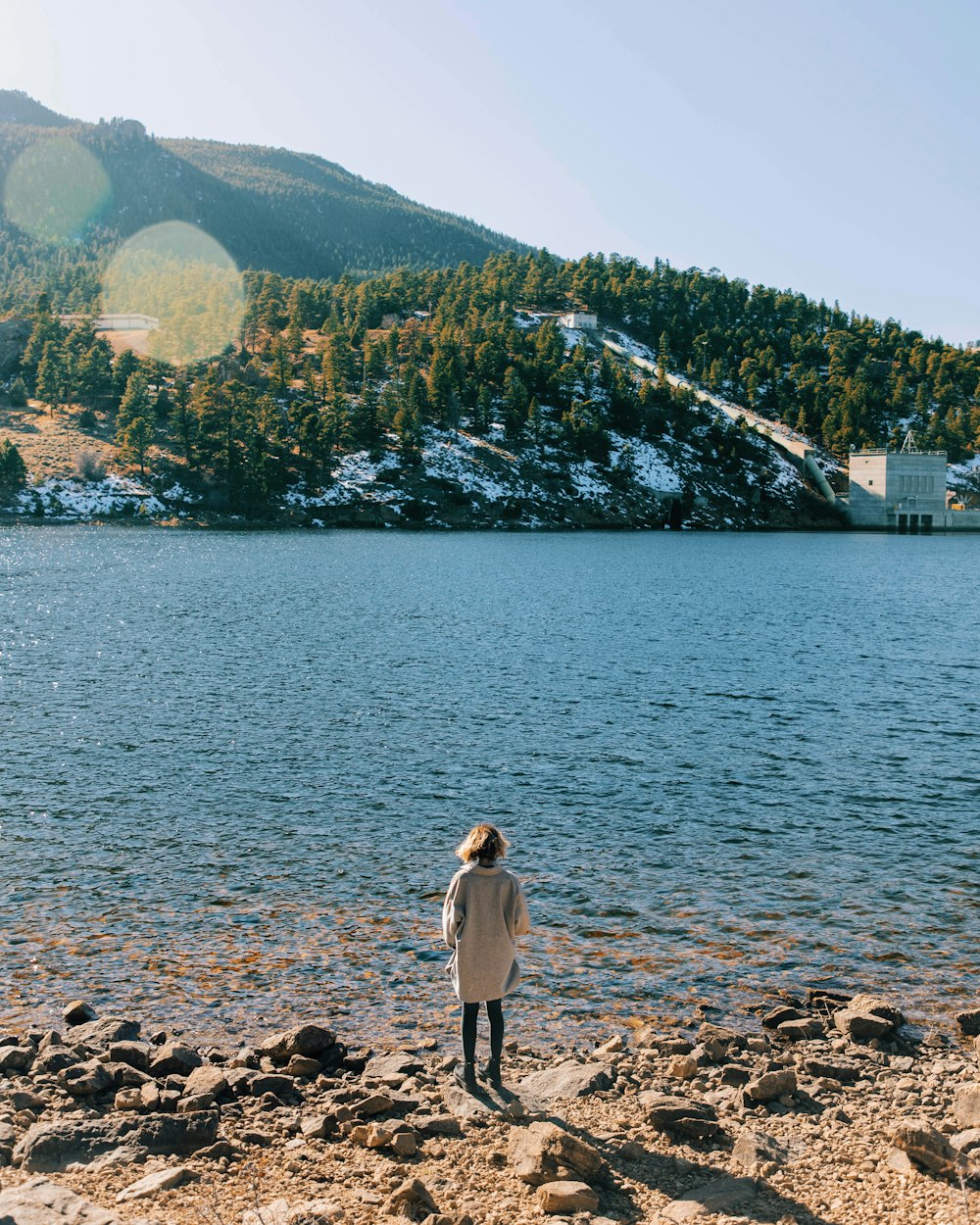 a woman standing on the shore of a lake