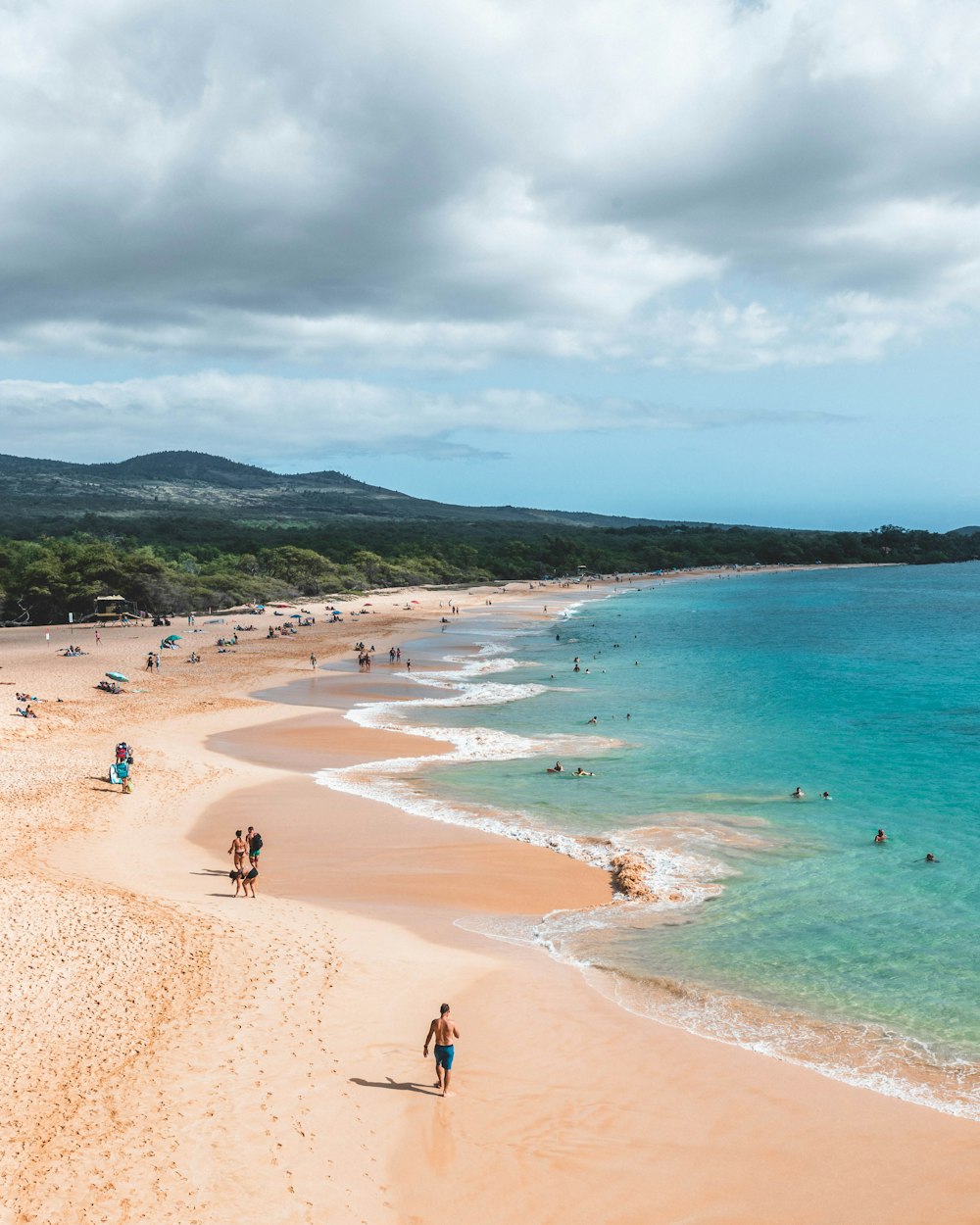 Un gruppo di persone che camminano lungo una spiaggia vicino all'oceano