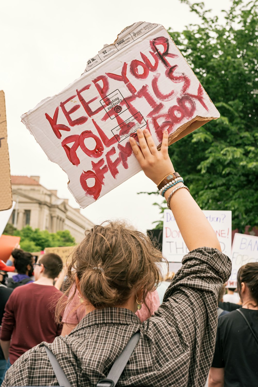 a woman holding a sign that says keep your politics alive