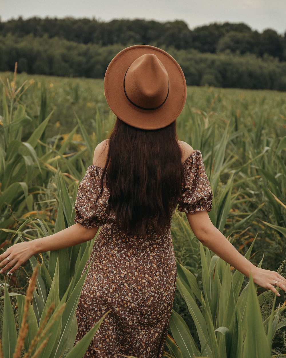 a woman wearing a brown hat standing in a field