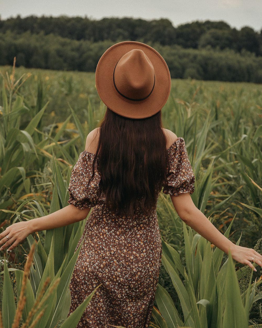 Eine Frau mit braunem Hut steht auf einem Feld