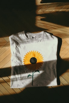 a white t - shirt with a yellow flower painted on it