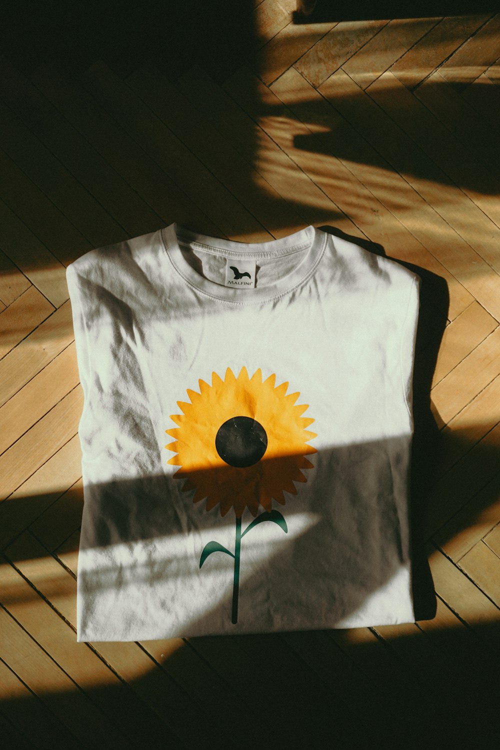 a white t - shirt with a yellow flower painted on it