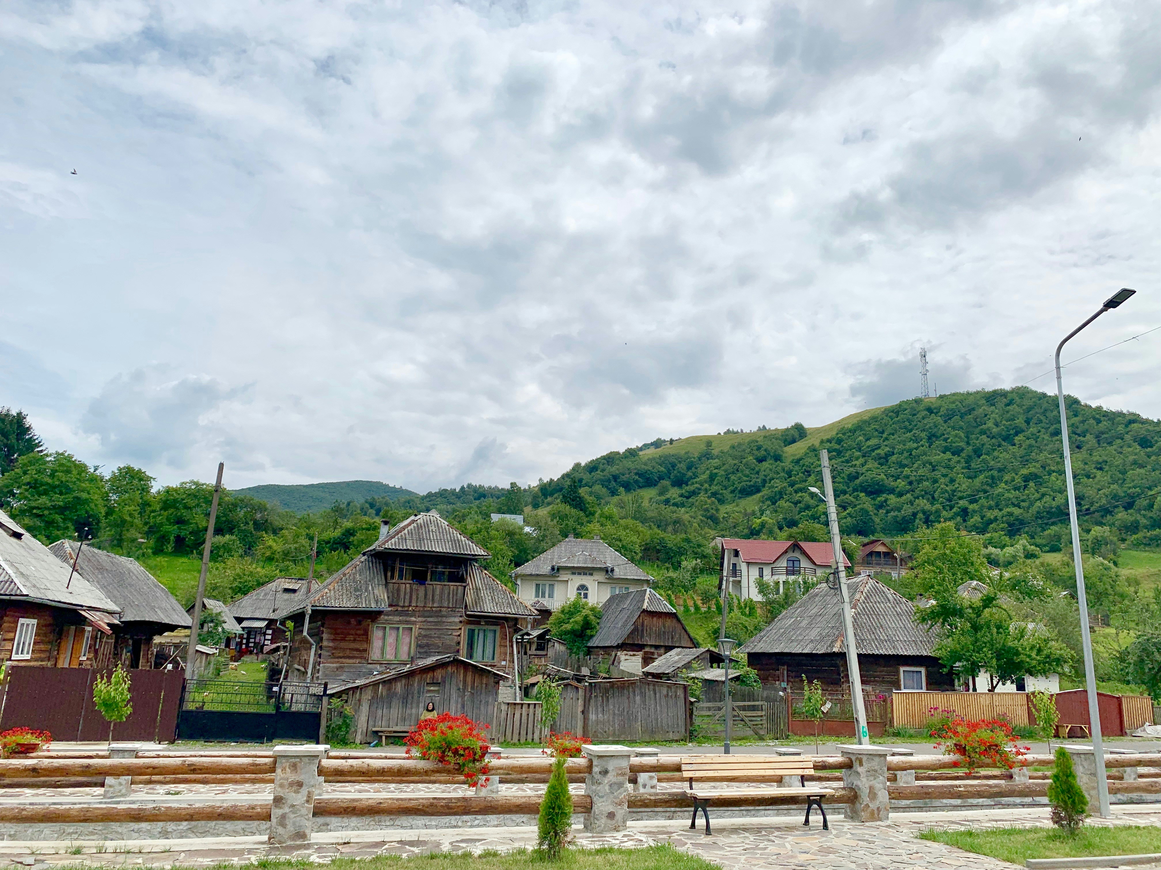 a row of wooden buildings sitting on top of a lush green hillside