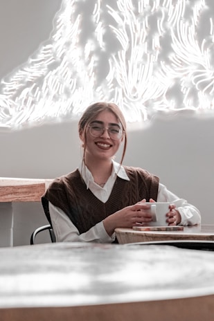 A smiling customer holding a late to the party adhd branded mug near a window with soft natural light.