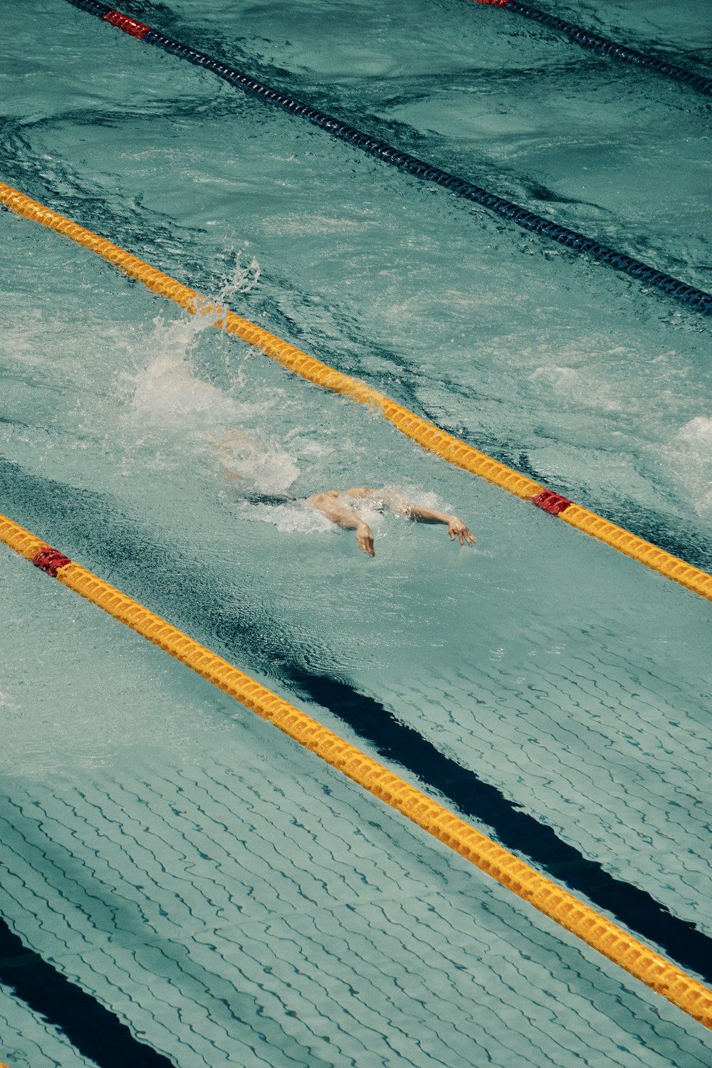 a person swimming in a pool with a yellow line