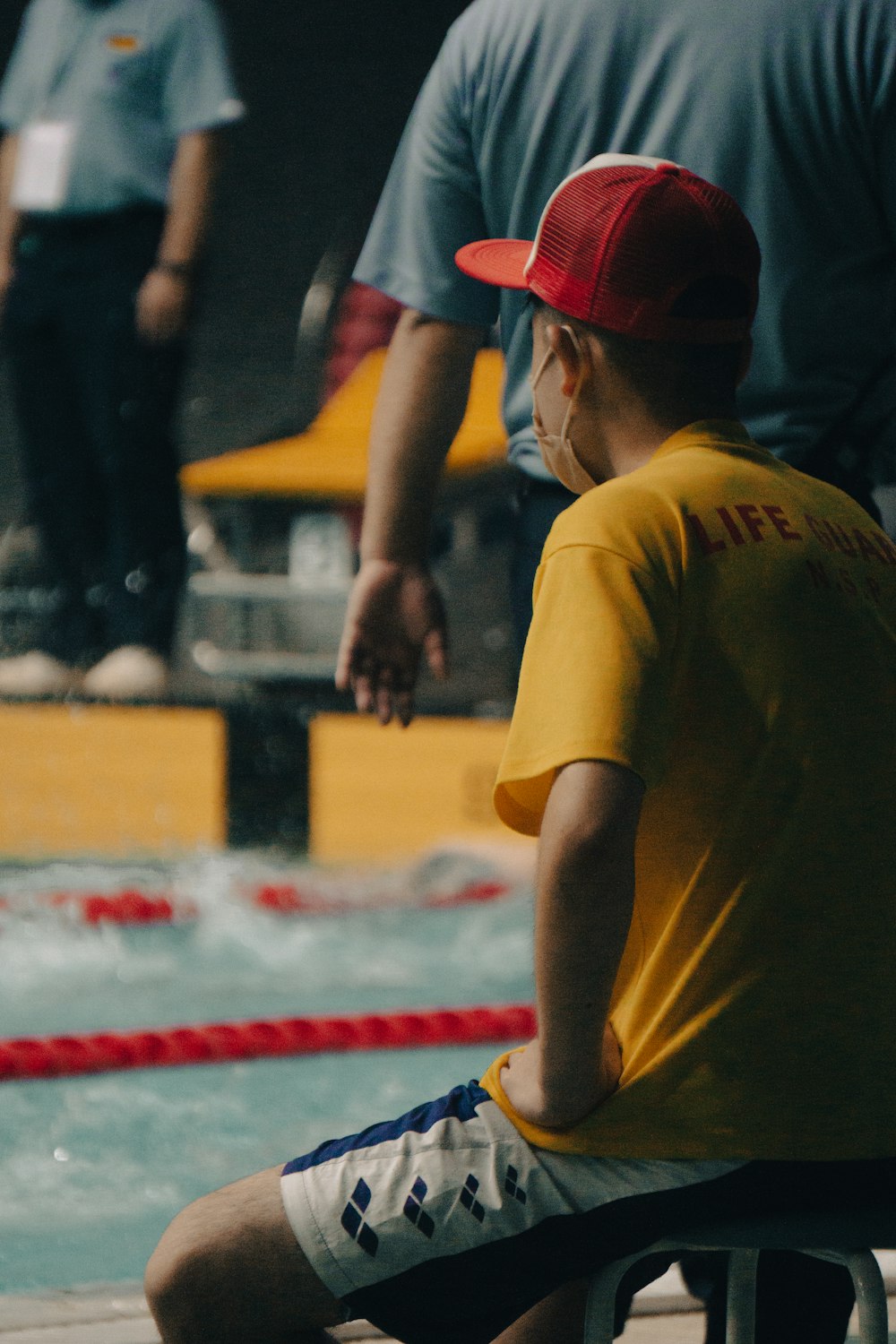 a man sitting on a bench next to a swimming pool