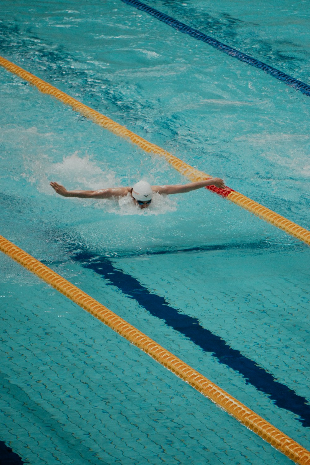 a man swimming in a pool wearing a white hat