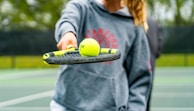 a person holding a tennis racket and two tennis balls