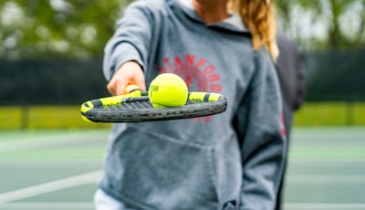 a person holding a tennis racket and two tennis balls