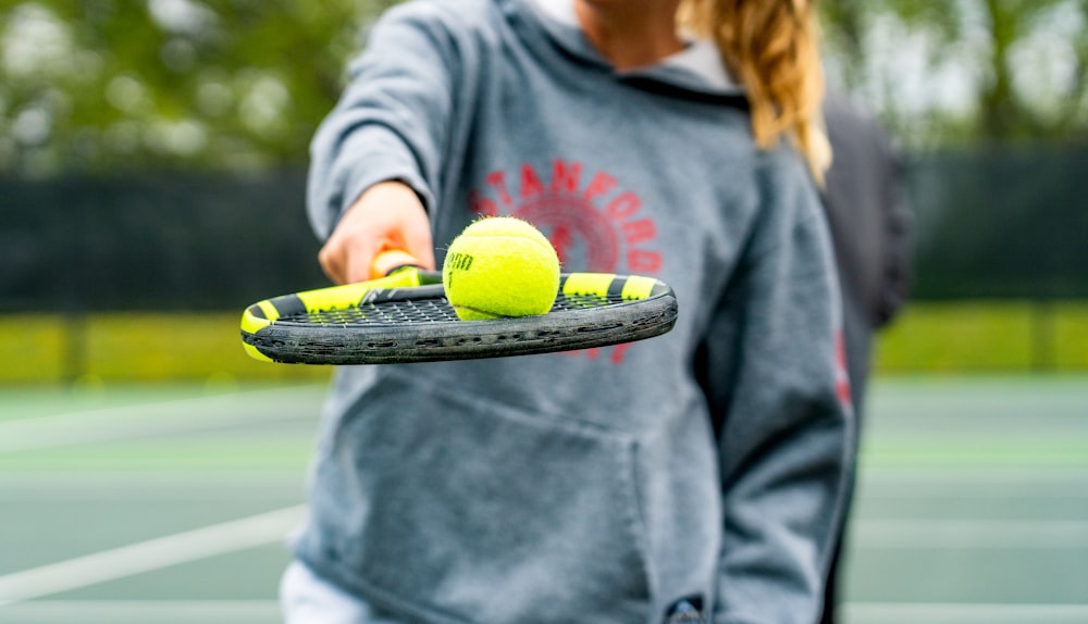 a person holding a tennis racket and two tennis balls