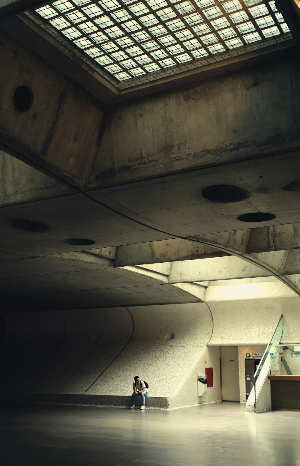 a person sitting on a bench under a skylight