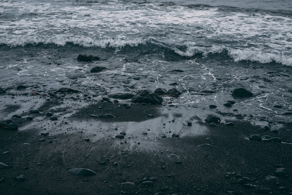 a black sand beach with waves crashing on it