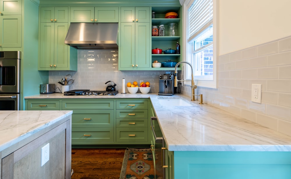 a kitchen with green cabinets and marble counter tops