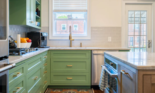 A kitchen with green cabinets and white counter tops