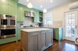 a kitchen with green cabinets and stainless steel appliances