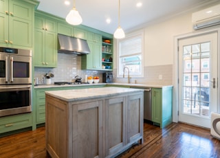 a kitchen with green cabinets and stainless steel appliances